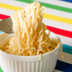A ramekin full of plain ramen noodles being lifted by a fork
